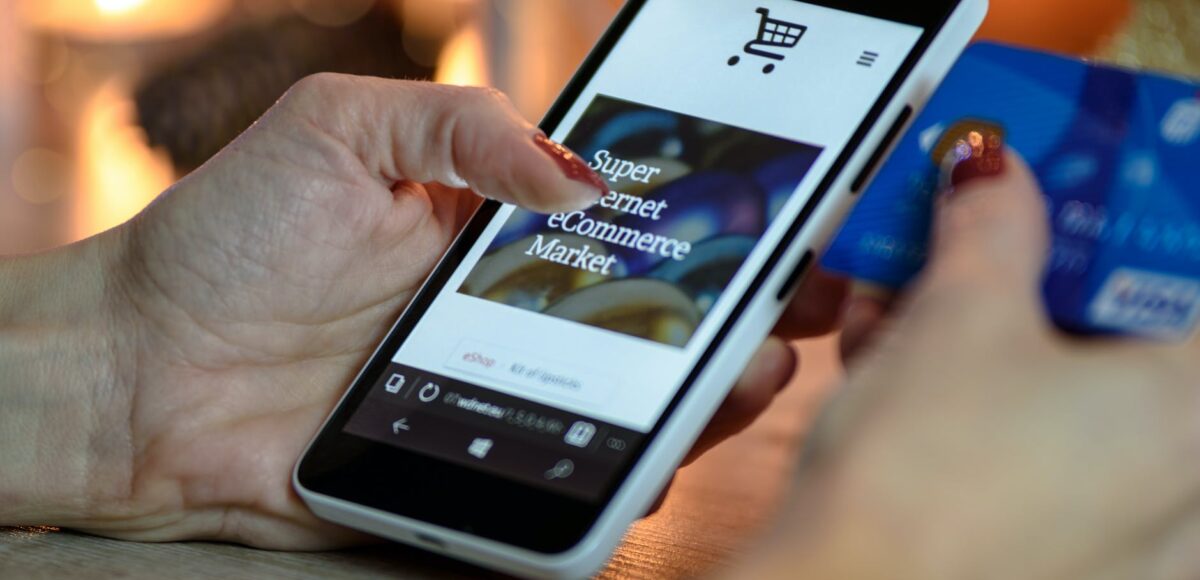 person using black and white smartphone and holding blue card