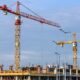 three yellow and red tower cranes under clear blue sky