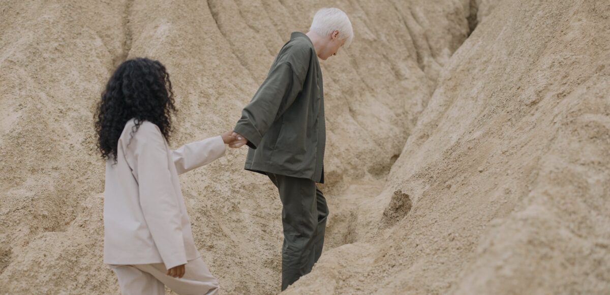 couple holding hands while walking on sand