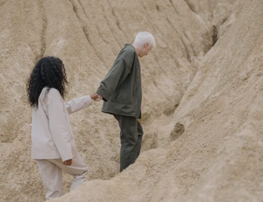 couple holding hands while walking on sand