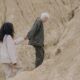 couple holding hands while walking on sand