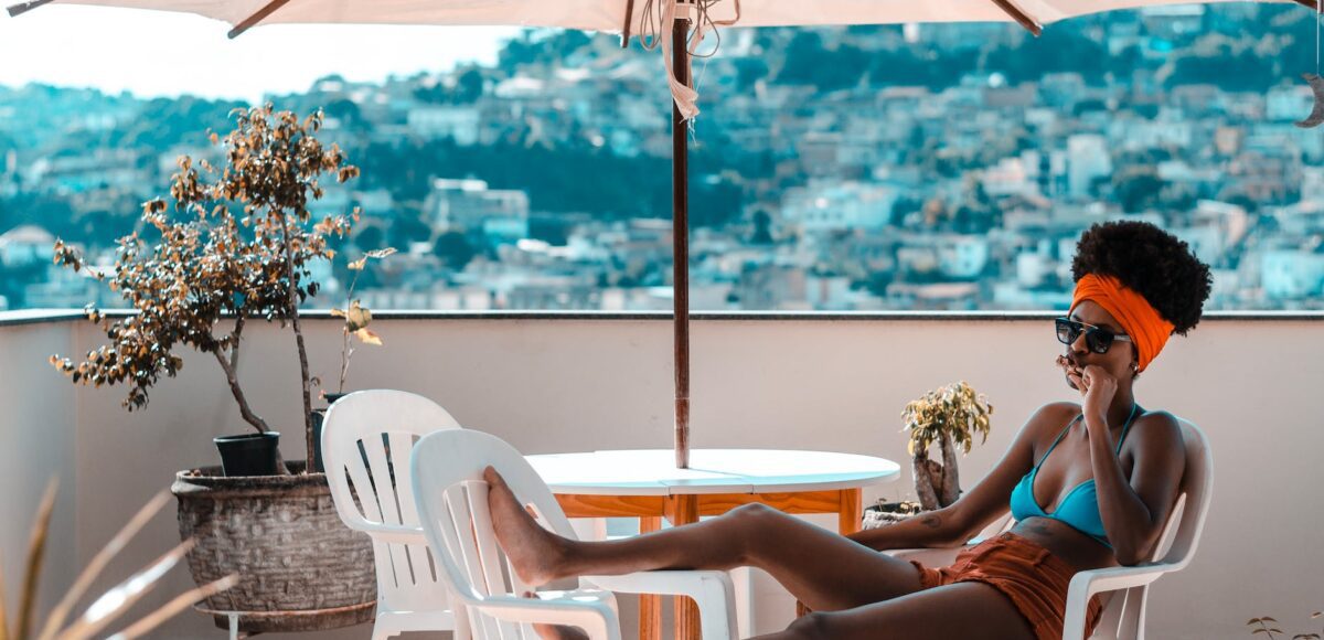 woman sitting on armchair under white patio umbrella