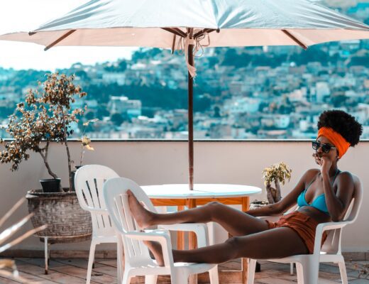 woman sitting on armchair under white patio umbrella