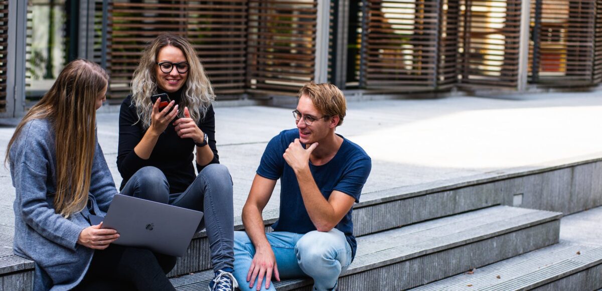 three persons sitting on the stairs talking with each other