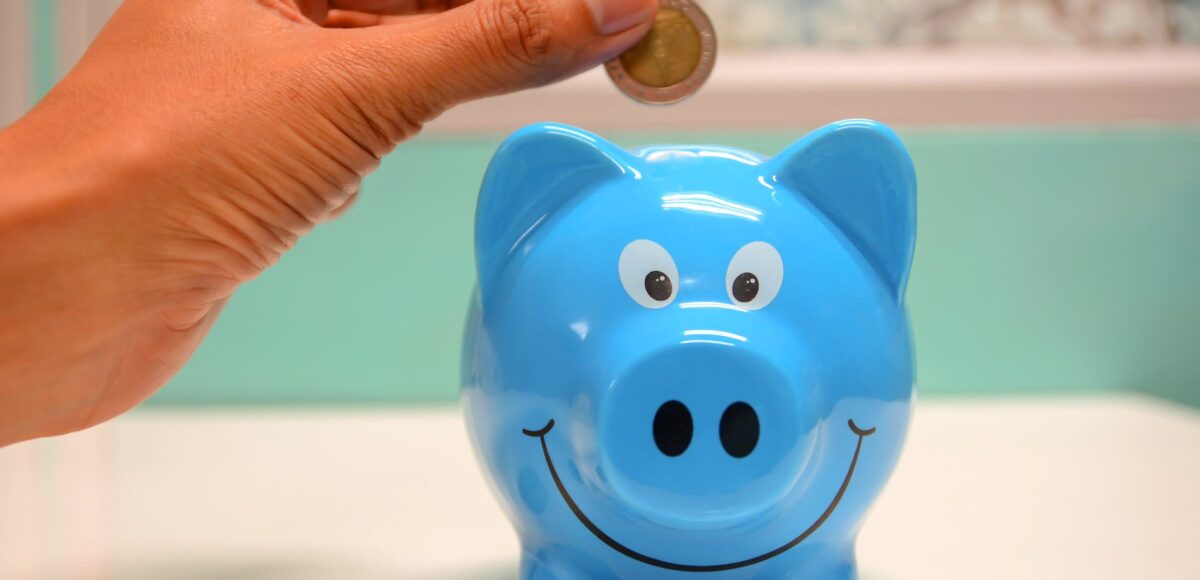 person putting coin in a piggy bank