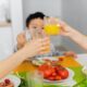 two women and boy toasting with glasses of juice during dinner