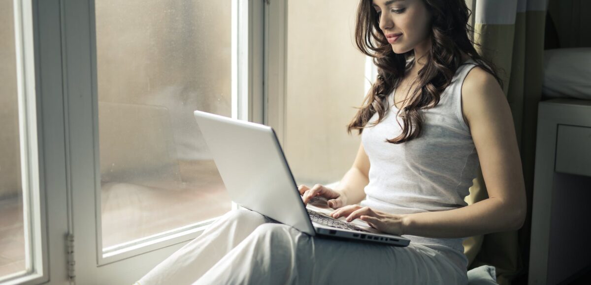 woman wearing tank top sitting by the window