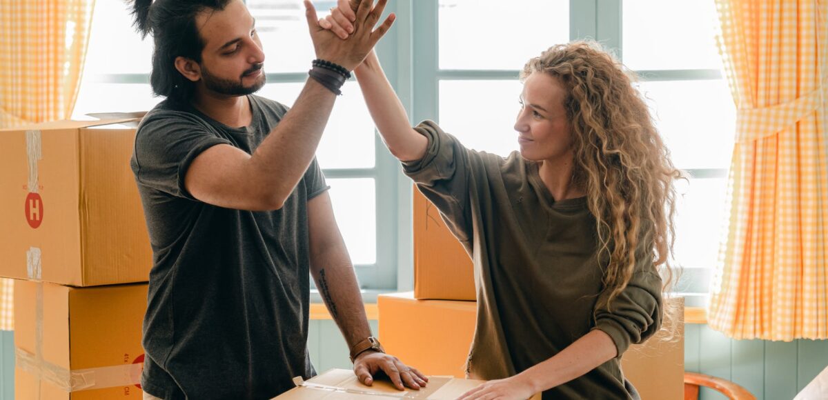 multiracial couple giving high give standing near pile of boxes